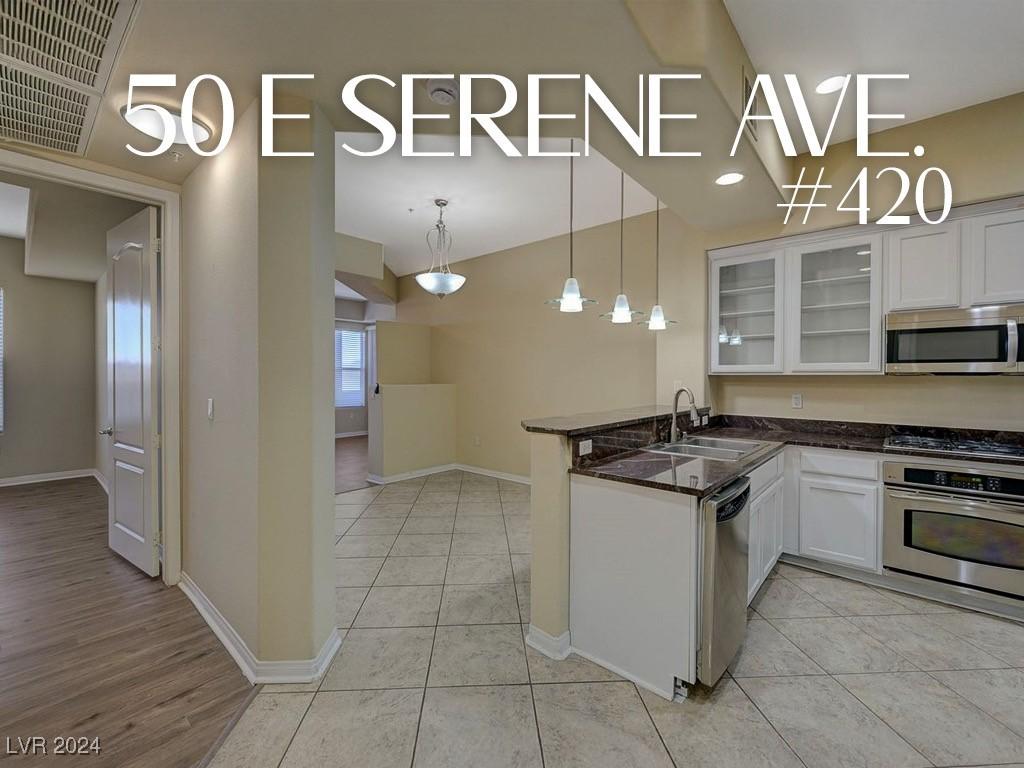 kitchen featuring pendant lighting, sink, appliances with stainless steel finishes, white cabinetry, and kitchen peninsula