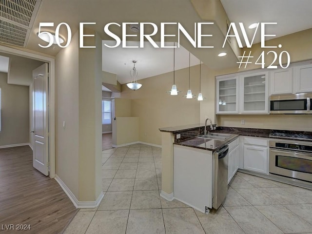 kitchen featuring pendant lighting, sink, appliances with stainless steel finishes, white cabinetry, and kitchen peninsula