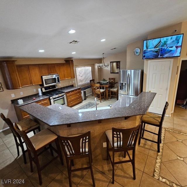 kitchen with kitchen peninsula, appliances with stainless steel finishes, an inviting chandelier, and sink