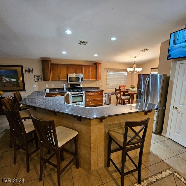 kitchen featuring a kitchen breakfast bar, stainless steel appliances, light tile patterned floors, decorative light fixtures, and a chandelier