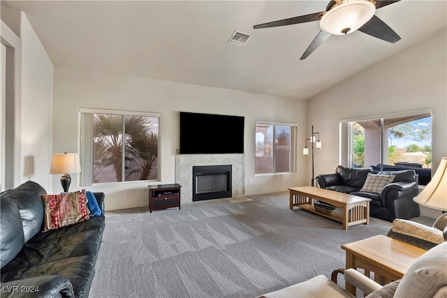 carpeted living room with a tile fireplace, ceiling fan, and vaulted ceiling