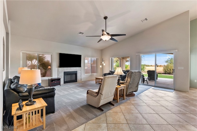 living room featuring ceiling fan, light tile patterned floors, high vaulted ceiling, and a tiled fireplace