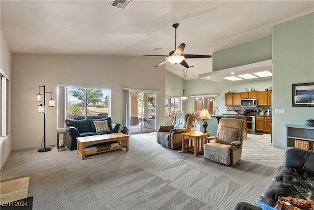 living room with ceiling fan, sink, high vaulted ceiling, and light colored carpet