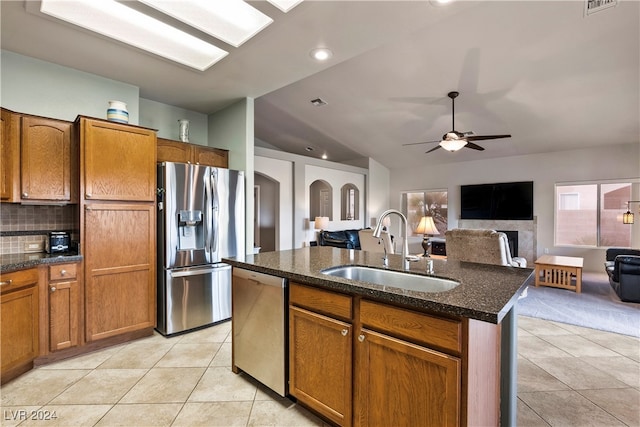 kitchen with appliances with stainless steel finishes, sink, light tile patterned floors, lofted ceiling, and an island with sink