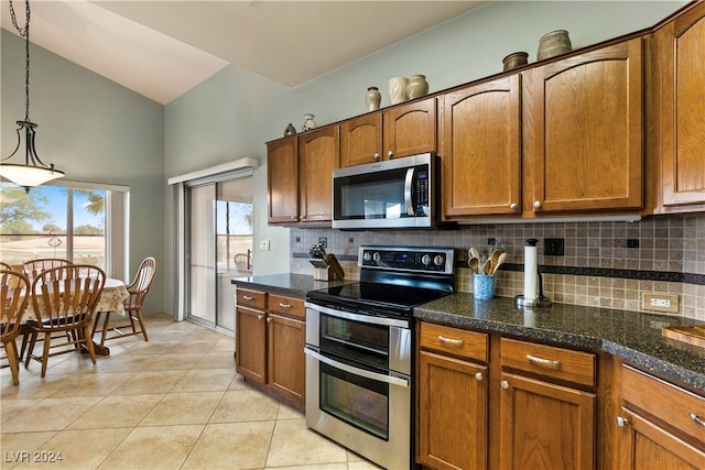 kitchen featuring decorative backsplash, stainless steel appliances, vaulted ceiling, decorative light fixtures, and light tile patterned flooring