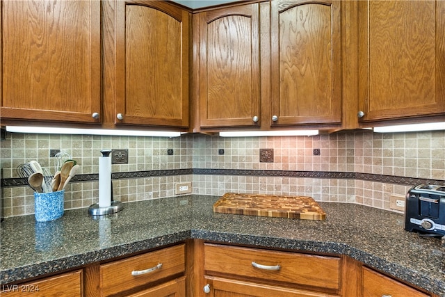 kitchen featuring decorative backsplash and dark stone counters