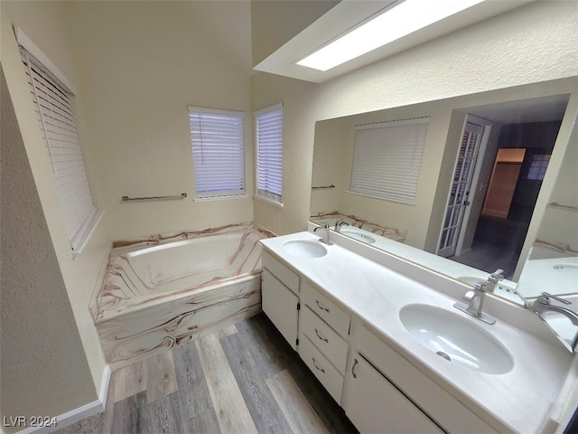 bathroom featuring hardwood / wood-style floors, vanity, a tub to relax in, and vaulted ceiling