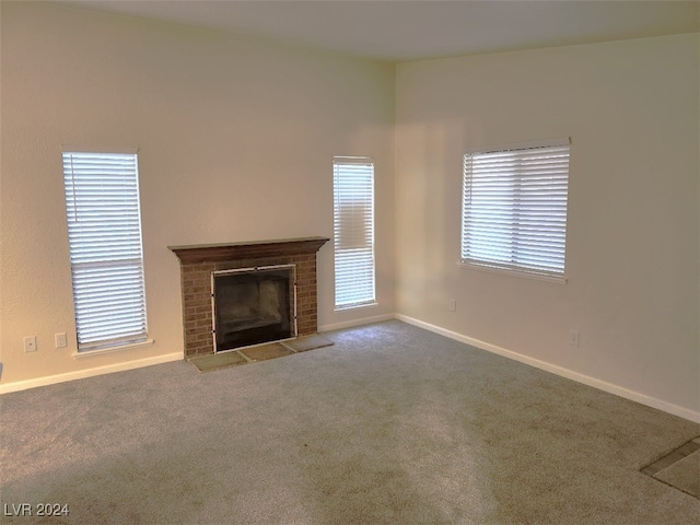 unfurnished living room featuring a fireplace, plenty of natural light, and carpet