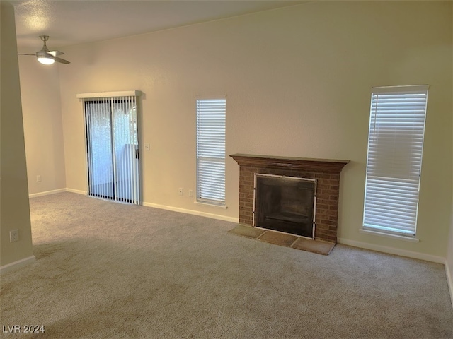 unfurnished living room featuring a fireplace, ceiling fan, and light carpet