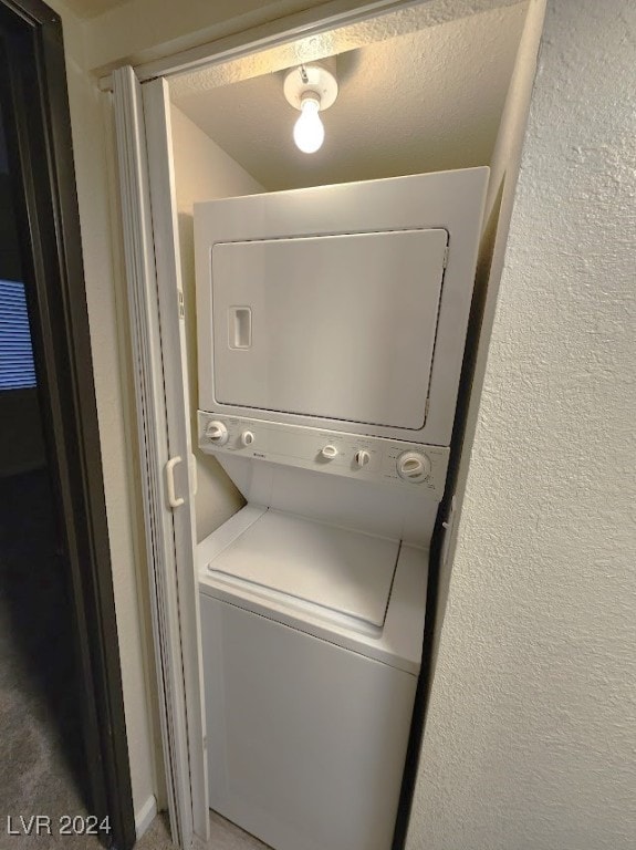 washroom with a textured ceiling and stacked washer / drying machine