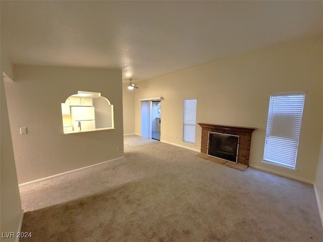 unfurnished living room featuring a fireplace, light carpet, and ceiling fan