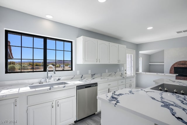 kitchen featuring sink, stainless steel dishwasher, light wood-type flooring, a fireplace, and white cabinetry