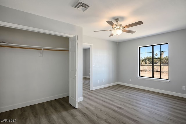 unfurnished bedroom with dark hardwood / wood-style flooring, a closet, and ceiling fan