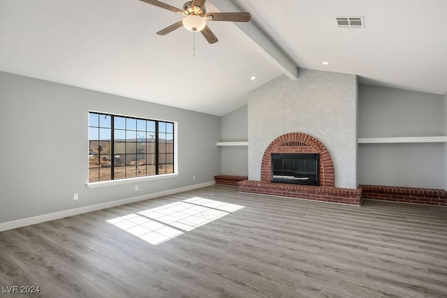 unfurnished living room featuring lofted ceiling with beams, light hardwood / wood-style floors, ceiling fan, and a brick fireplace