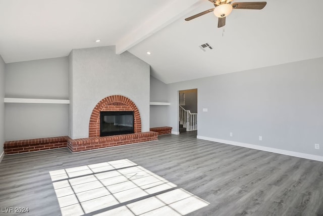 unfurnished living room with hardwood / wood-style floors, lofted ceiling with beams, a brick fireplace, and ceiling fan