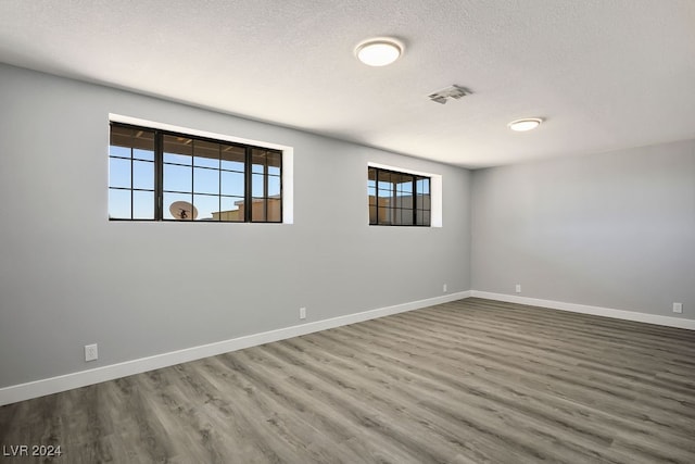 unfurnished room with wood-type flooring and a textured ceiling