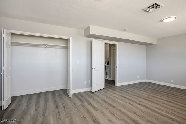 unfurnished bedroom featuring a closet, dark wood-type flooring, and a textured ceiling