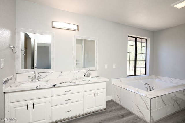 bathroom featuring hardwood / wood-style floors, vanity, and tiled tub