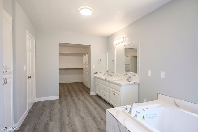 bathroom with a washtub, wood-type flooring, and vanity