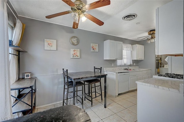 kitchen featuring a textured ceiling, light tile patterned floors, dishwasher, white cabinets, and stainless steel gas stovetop