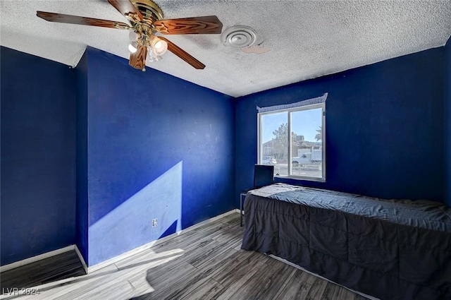 bedroom with ceiling fan, wood-type flooring, and a textured ceiling