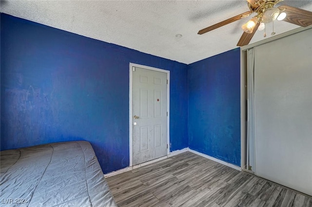 unfurnished bedroom featuring hardwood / wood-style floors, a textured ceiling, vaulted ceiling, and ceiling fan