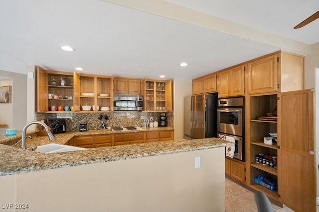 kitchen featuring sink, decorative backsplash, appliances with stainless steel finishes, light stone counters, and kitchen peninsula