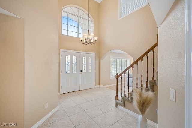 entrance foyer featuring a notable chandelier, plenty of natural light, a towering ceiling, and light tile patterned floors