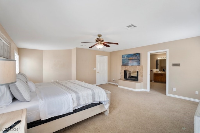 carpeted bedroom with ceiling fan, a multi sided fireplace, and connected bathroom