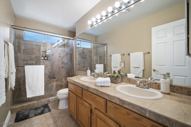 bathroom with tile patterned floors, vanity, toilet, and a shower with door