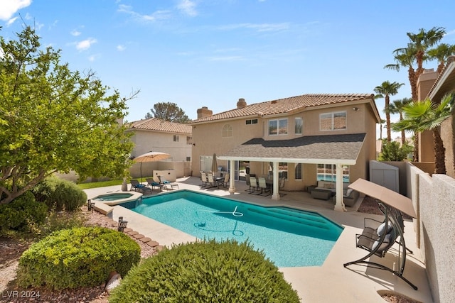 rear view of property featuring a swimming pool with hot tub, a patio, and an outdoor living space