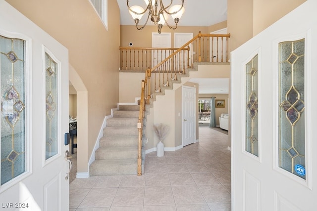 tiled entryway featuring a towering ceiling and an inviting chandelier