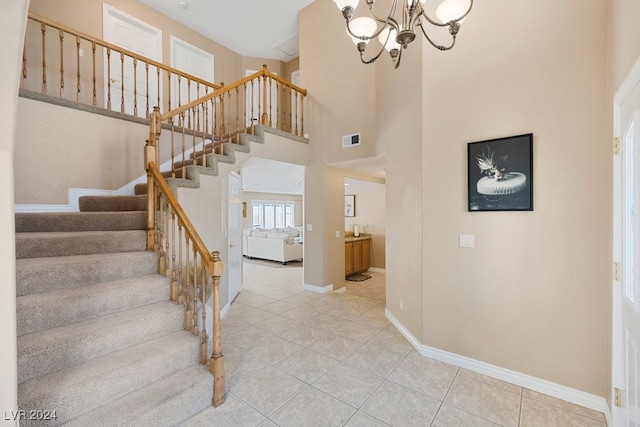 stairway featuring tile patterned floors, a notable chandelier, and a towering ceiling