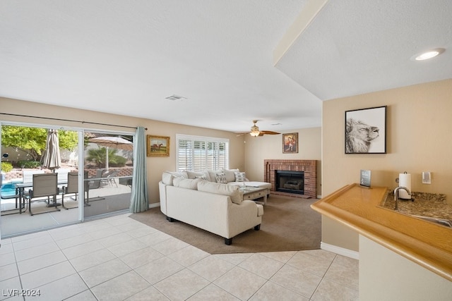 tiled living room with ceiling fan, sink, and a brick fireplace