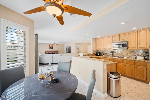 kitchen featuring light tile patterned floors, gas stovetop, light stone counters, and tasteful backsplash