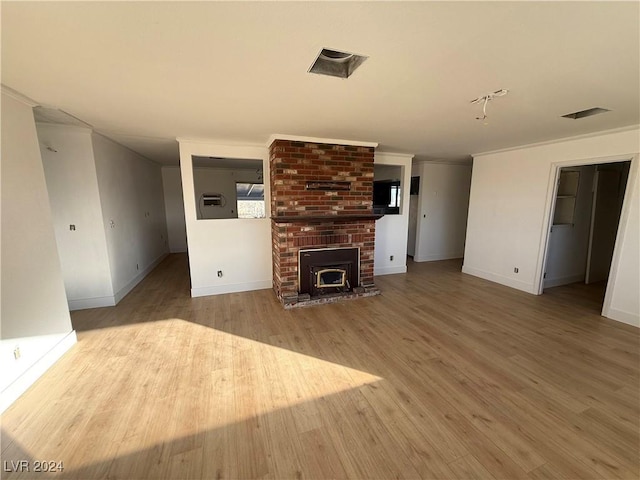 unfurnished living room featuring light wood-type flooring, a brick fireplace, and crown molding