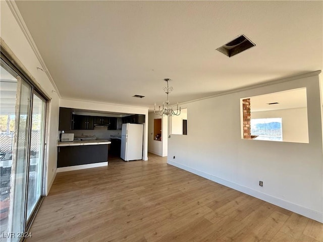 unfurnished living room featuring crown molding, light hardwood / wood-style flooring, a wealth of natural light, and a chandelier