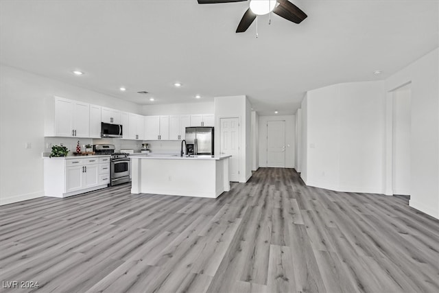 kitchen featuring ceiling fan, white cabinetry, an island with sink, appliances with stainless steel finishes, and light wood-type flooring