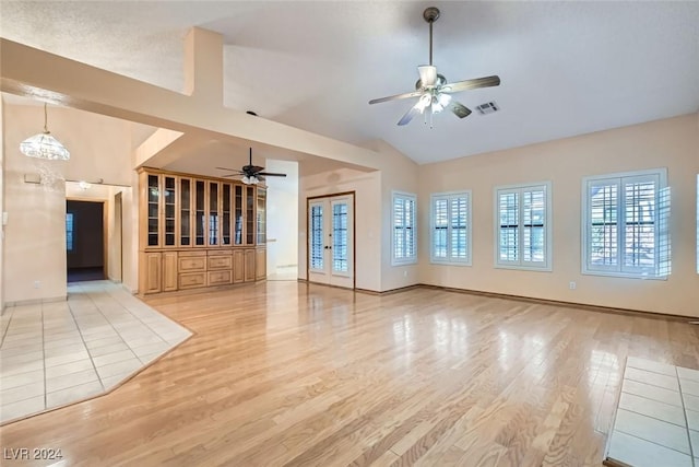 unfurnished living room featuring ceiling fan, light hardwood / wood-style floors, a wealth of natural light, and vaulted ceiling