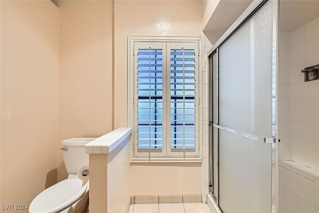 bathroom featuring tile patterned floors, toilet, and a shower with shower door