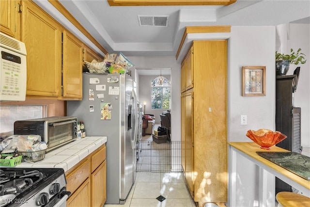 kitchen featuring tile counters, light tile patterned flooring, and stainless steel refrigerator with ice dispenser