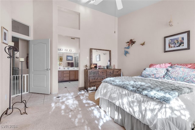 bedroom featuring light carpet, a high ceiling, ensuite bathroom, and ceiling fan