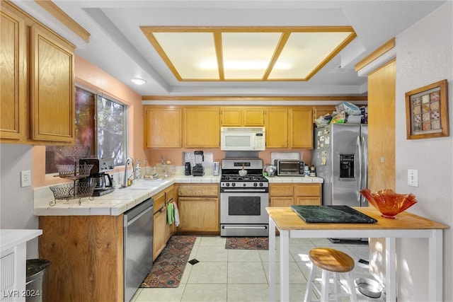 kitchen with tile countertops, light tile patterned floors, stainless steel appliances, and sink