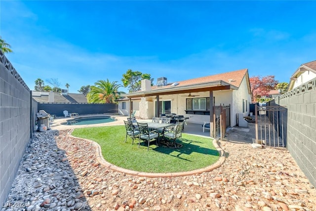 rear view of house featuring a fenced in pool, a patio area, ceiling fan, and a lawn