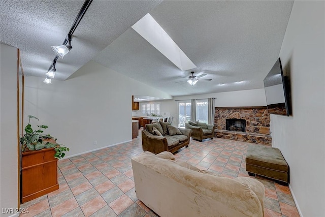 living room featuring a textured ceiling, ceiling fan, a fireplace, and track lighting