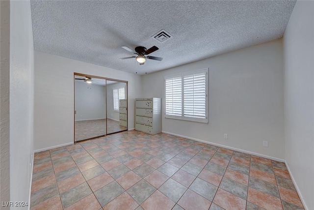 unfurnished bedroom featuring ceiling fan, a textured ceiling, and a closet