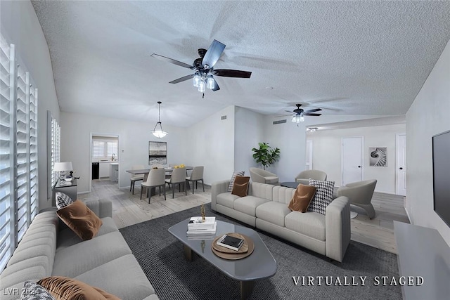 living room featuring hardwood / wood-style flooring, ceiling fan, and a textured ceiling