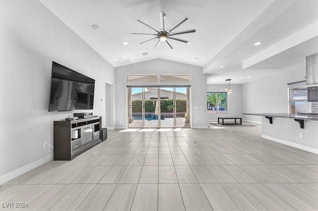 living room featuring vaulted ceiling, light tile patterned floors, and ceiling fan with notable chandelier