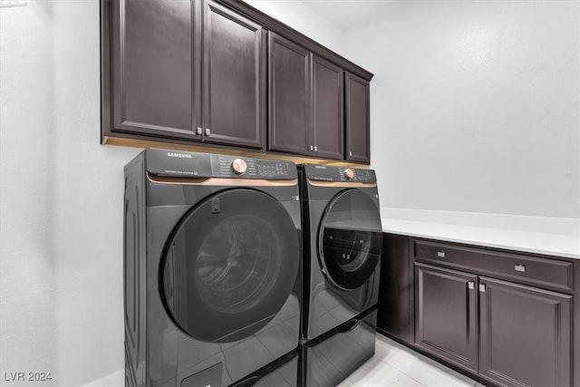 clothes washing area featuring washing machine and dryer and cabinets