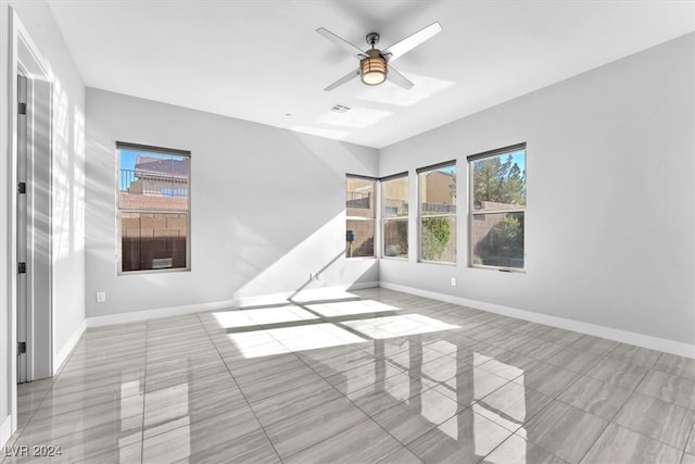 tiled empty room featuring a wealth of natural light and ceiling fan